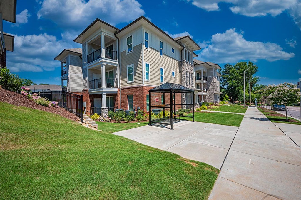 a sidewalk in front of an apartment building with a gazebo
