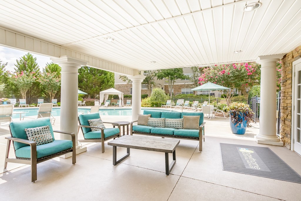 a covered patio with blue chairs and a pool