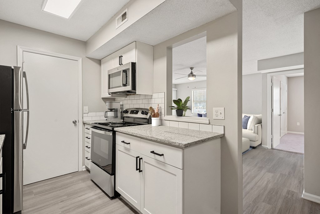 an open kitchen with white cabinets and stainless steel appliances