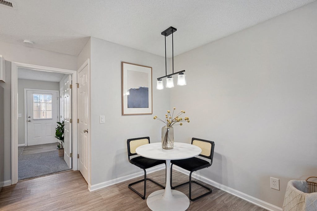 a dining room with a white table and two black chairs