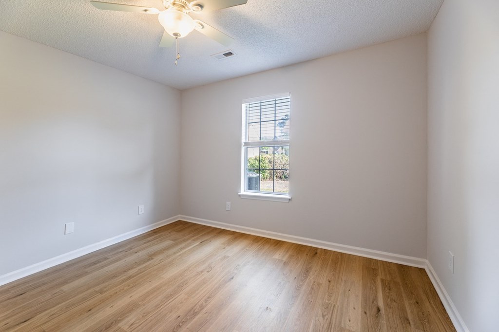 Empty room with a window and wooden floor.