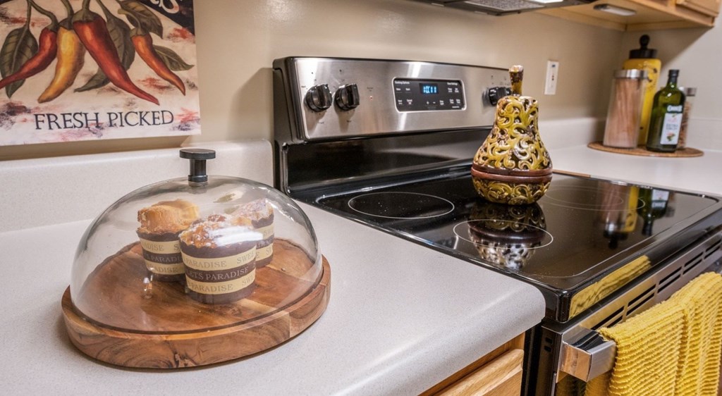 A kitchen with a stove top oven and a wooden tray with food on it at Palmetto Pointe apartments in Myrtle Beach, SC.