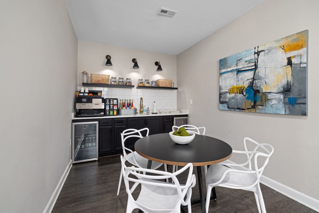 a dining area with a table and chairs and a kitchen in the background