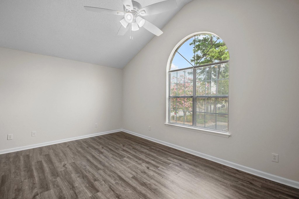 an empty bedroom with a large window and a ceiling fan