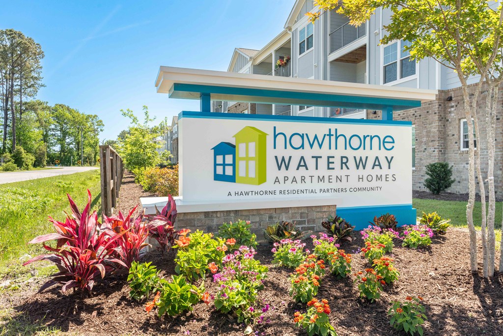 the sign for hawthorne waterway apartment homes with flowers in front of it