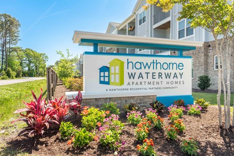 the sign for hawthorne waterway apartment homes with flowers in front of it
