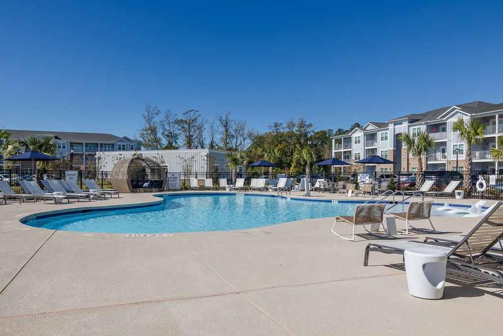 our resort style swimming pool is surrounded by lounge chairs and umbrellas