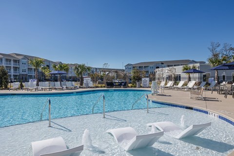 a swimming pool with chairs and umbrellas at the resort on a sunny day