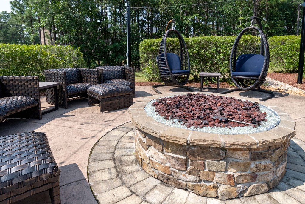 a patio with a fire pit and lounge chairs
