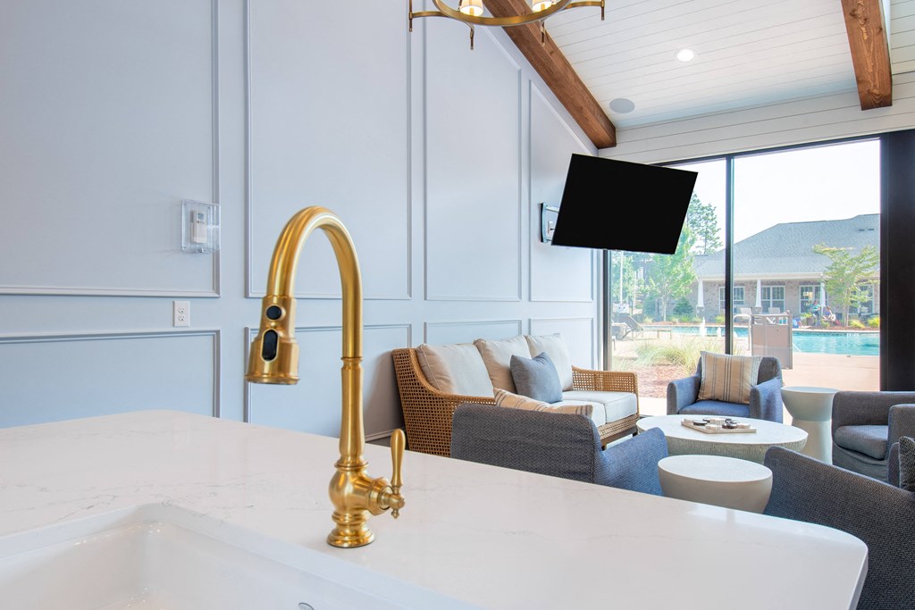 a kitchen with a white counter top and a white sink with a gold faucet