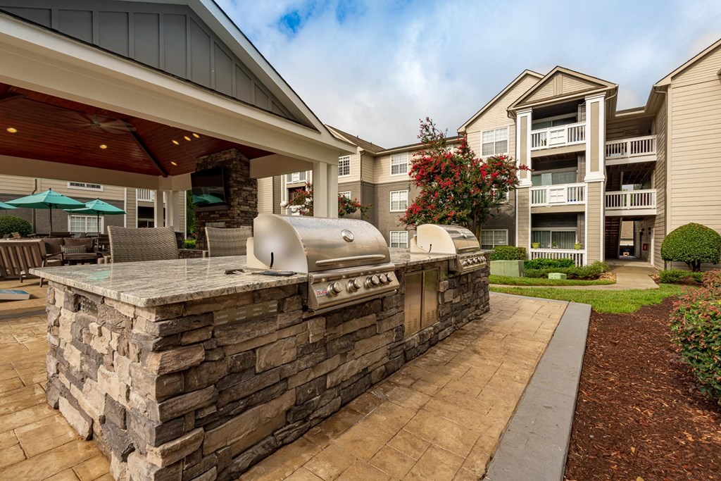 an outdoor kitchen with a grill and a stone wall