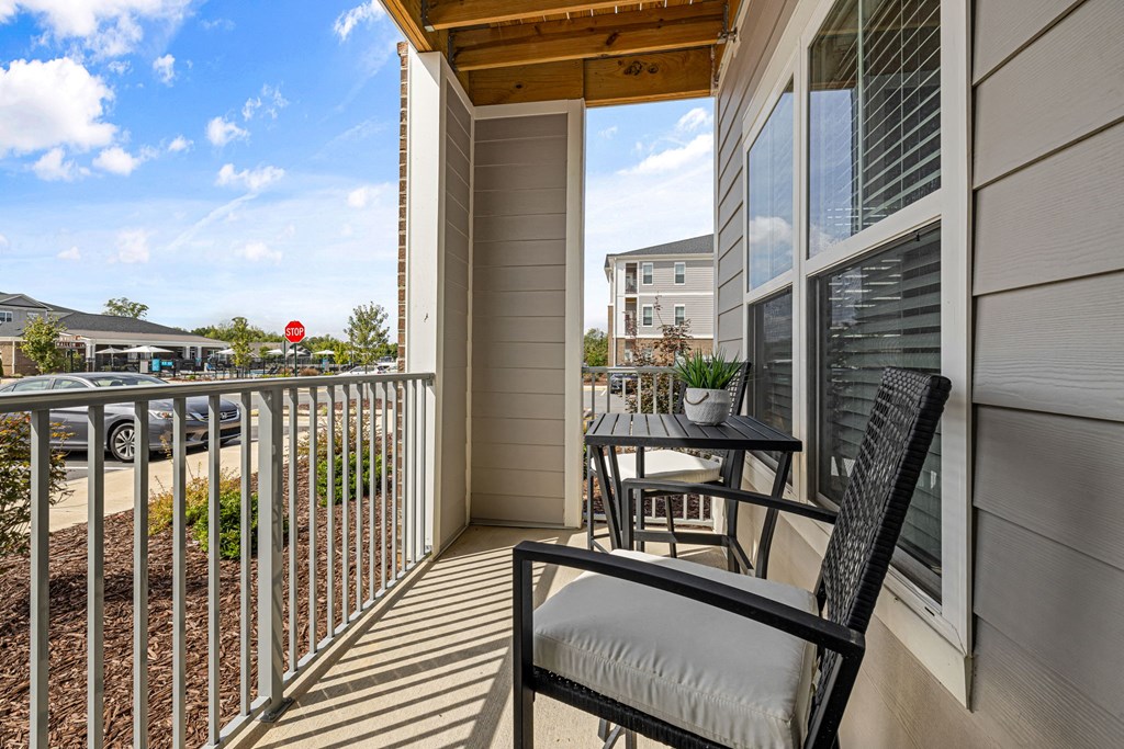 a balcony with a table and two chairs and a view of a street