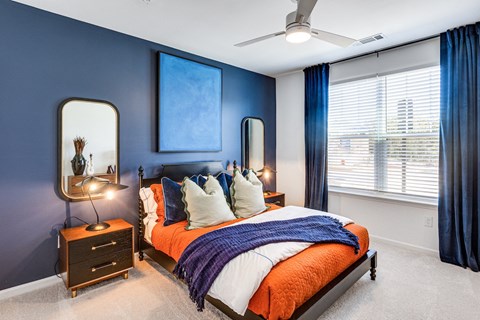 a bedroom with blue walls and a bed with white and orange pillows