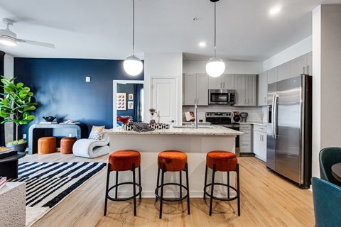an open kitchen and living room with a bar and stools