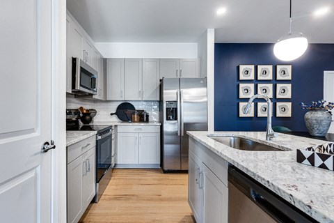 a kitchen with white cabinets and granite counter tops and a stainless steel refrigerator