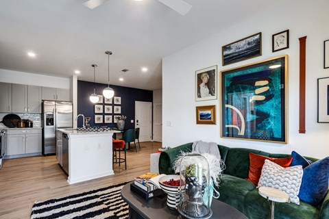 a living room with a green couch and a kitchen in the background
