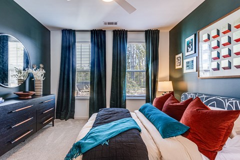 a bedroom with a bed with red and blue pillows and blue curtains