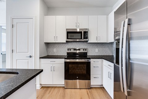 a modern kitchen with stainless steel appliances and white cabinets