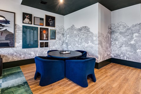a dining room with blue chairs and a table and a wall mural of a forest