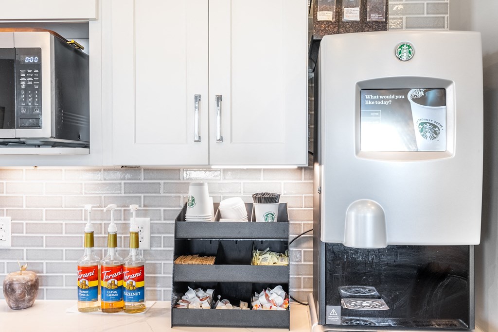 a kitchen with white cabinets and a microwave and a drawer with food in it