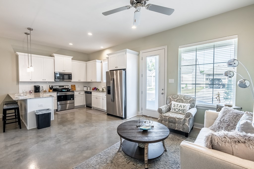 a living room with a couch and a table in front of a kitchen