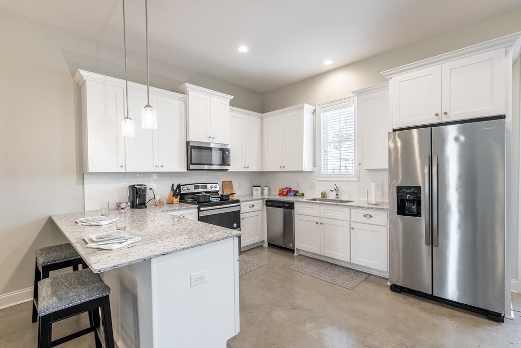 a large kitchen with stainless steel appliances and white cabinets