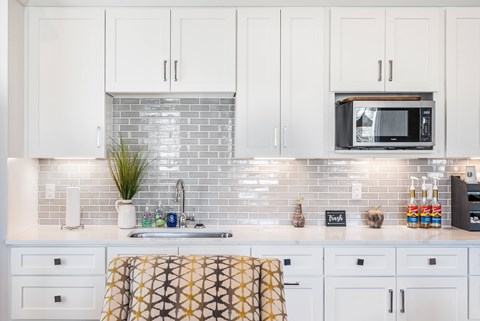 A kitchen with white cabinets and a brick backsplash.