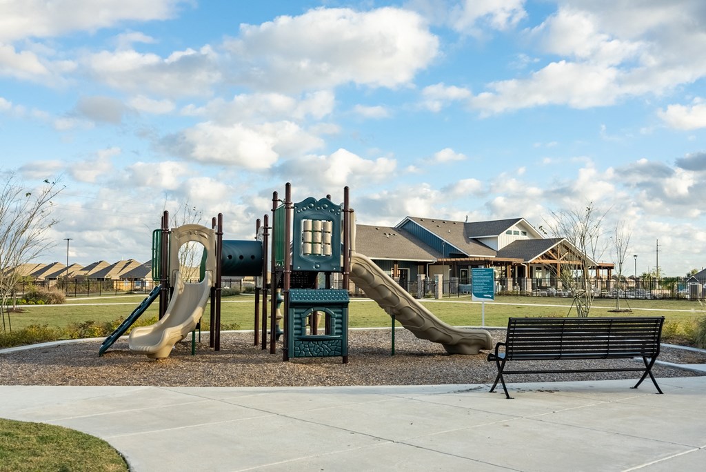 a playground with two slides and a bench in front of a house