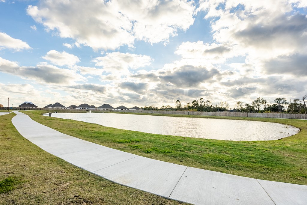 a path next to a body of water on a cloudy day