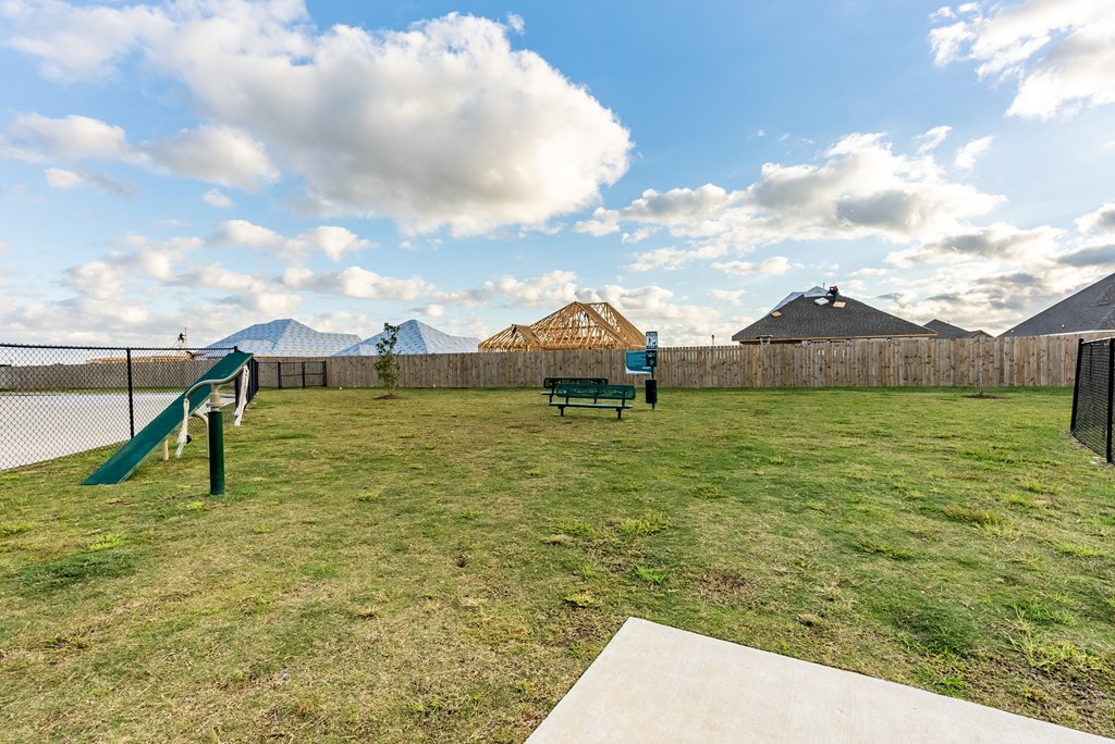 a backyard with a park bench and a chain link fence
