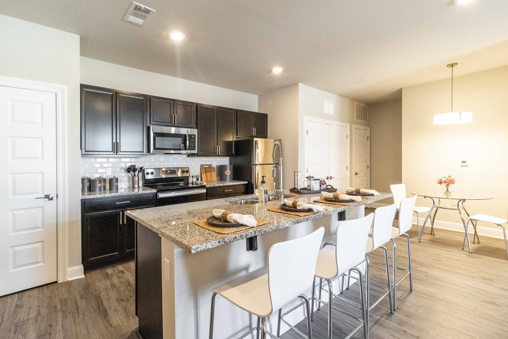 a kitchen with a large island with white chairs