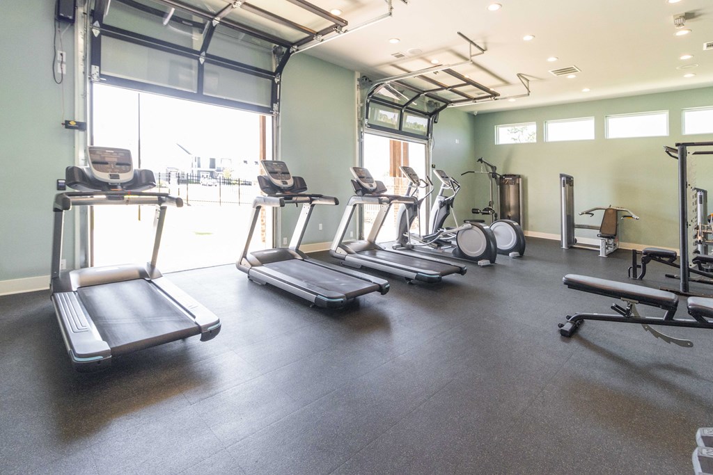 a gym with cardio equipment and a large window