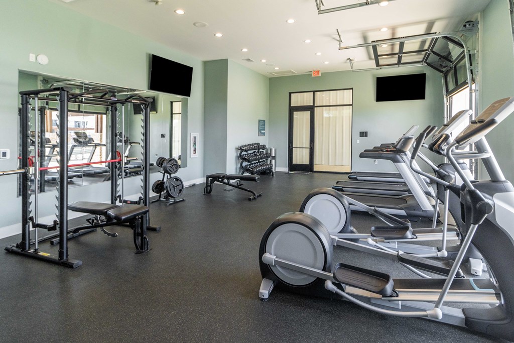 a gym with cardio equipment and weights on the floor