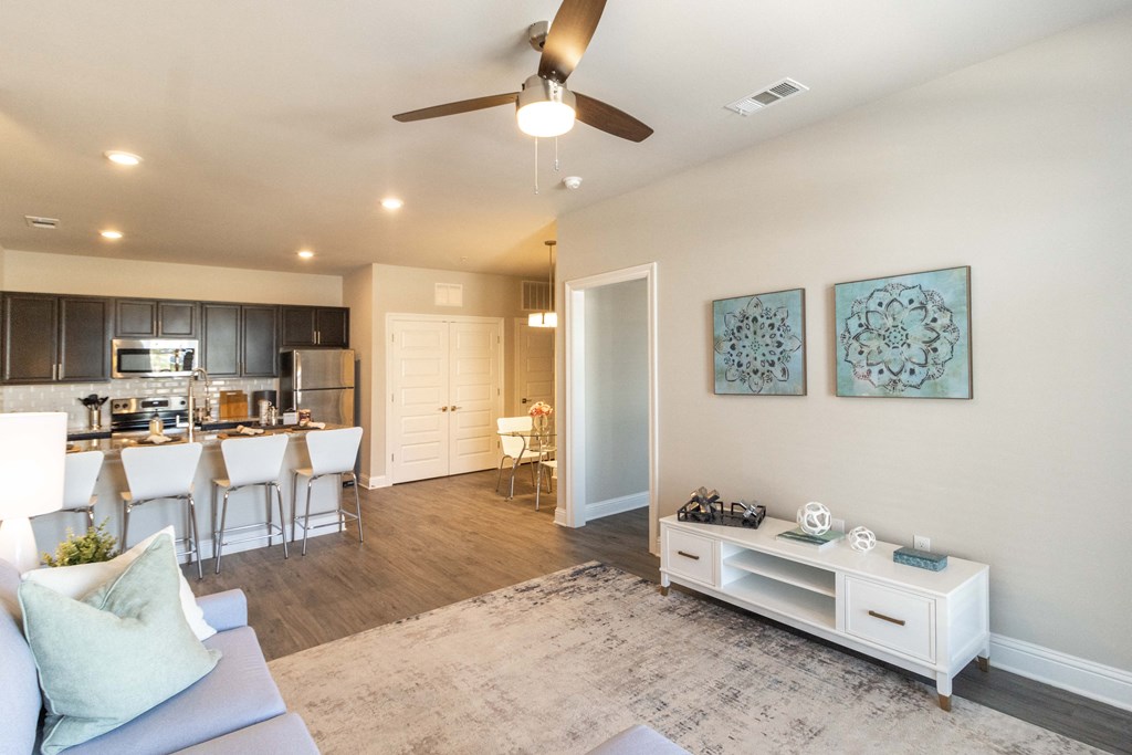a living room with a kitchen and a ceiling fan
