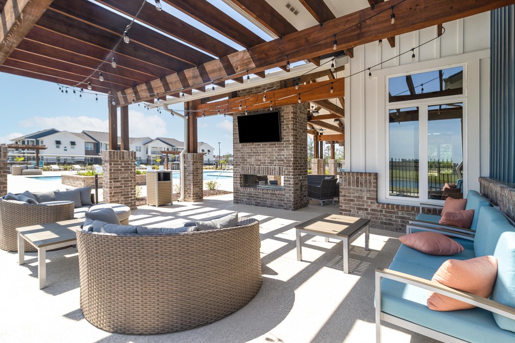 a covered patio with couches and chairs and a fireplace
