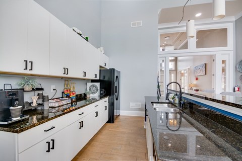 A kitchen with white cabinets and a black counter top.