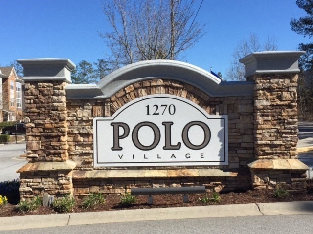 a sign for polo village on the side of a street