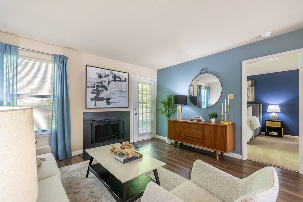 A living room with a fireplace, a chair, a couch, a coffee table, and a mirror at Hawthorne at Oak Ridge in Greensboro, NC.