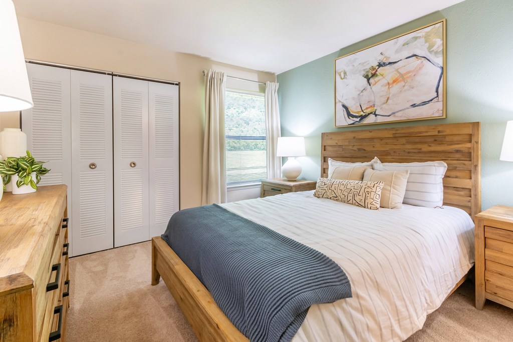 A bedroom with a large bed and a painting on the wall at Hawthorne at Oak Ridge in Greensboro, NC.