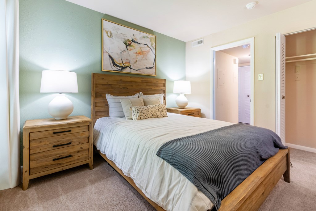 A bedroom with a bed, nightstands, and a painting on the wall at Hawthorne at Oak Ridge in Greensboro, NC.