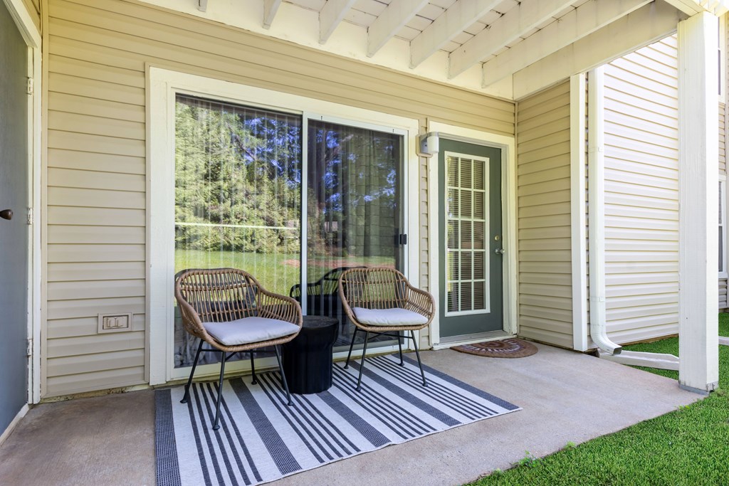 Two chairs are on a porch with a striped rug at Hawthorne at Oak Ridge in Greensboro, NC.