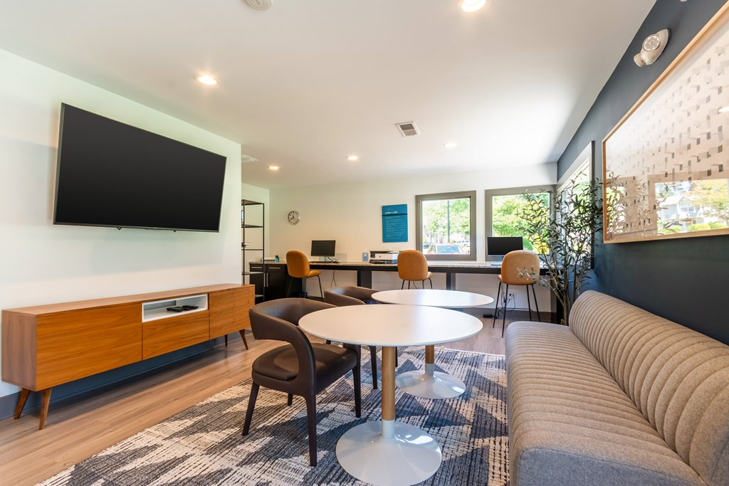 A modern living room with a flat screen TV mounted on the wall at Hawthorne at Oak Ridge in Greensboro, NC.