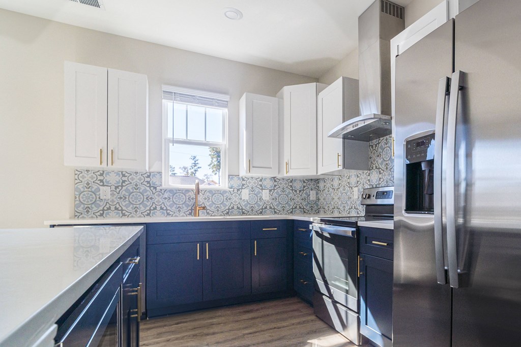 a kitchen with blue and white cabinets and stainless steel appliances