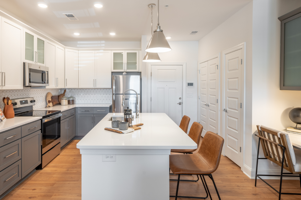 an open kitchen with a white counter top and a white island with chairs
