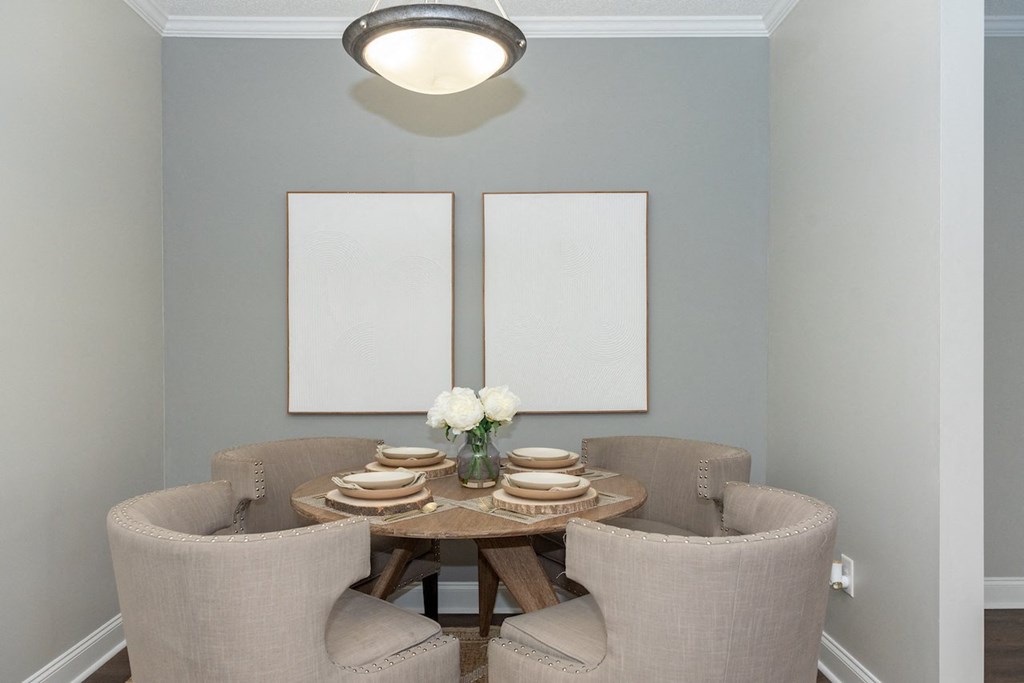 a dining room with a table and chairs and two paintings on the wall