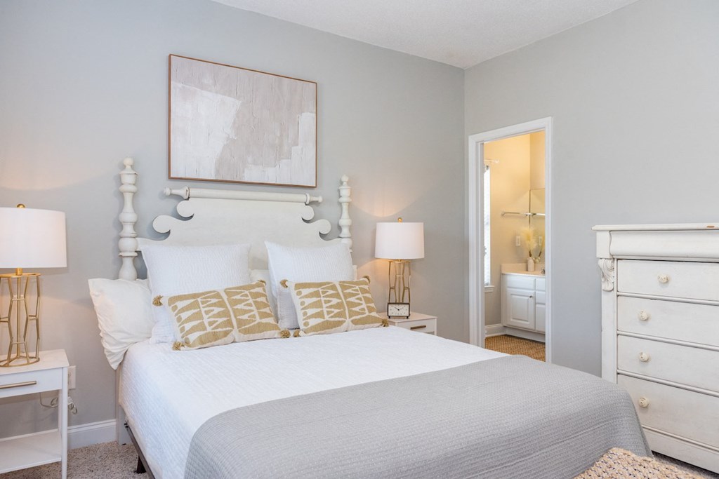 a bedroom with a white bed and a white dresser