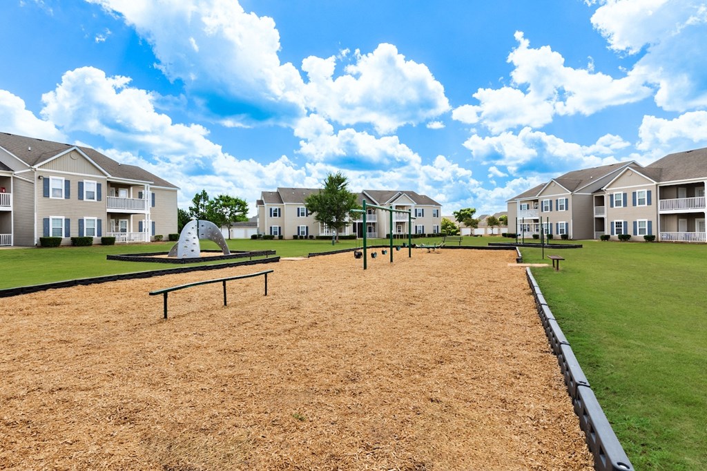 an empty park with benches in front of an apartment building