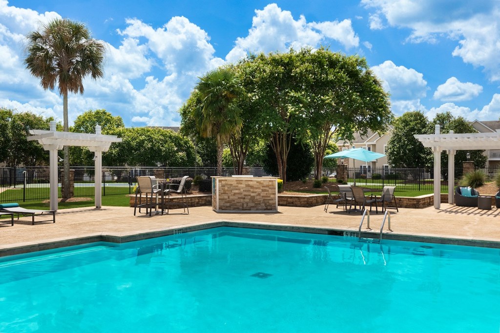 a swimming pool with chairs and umbrellas next to a resort style pool