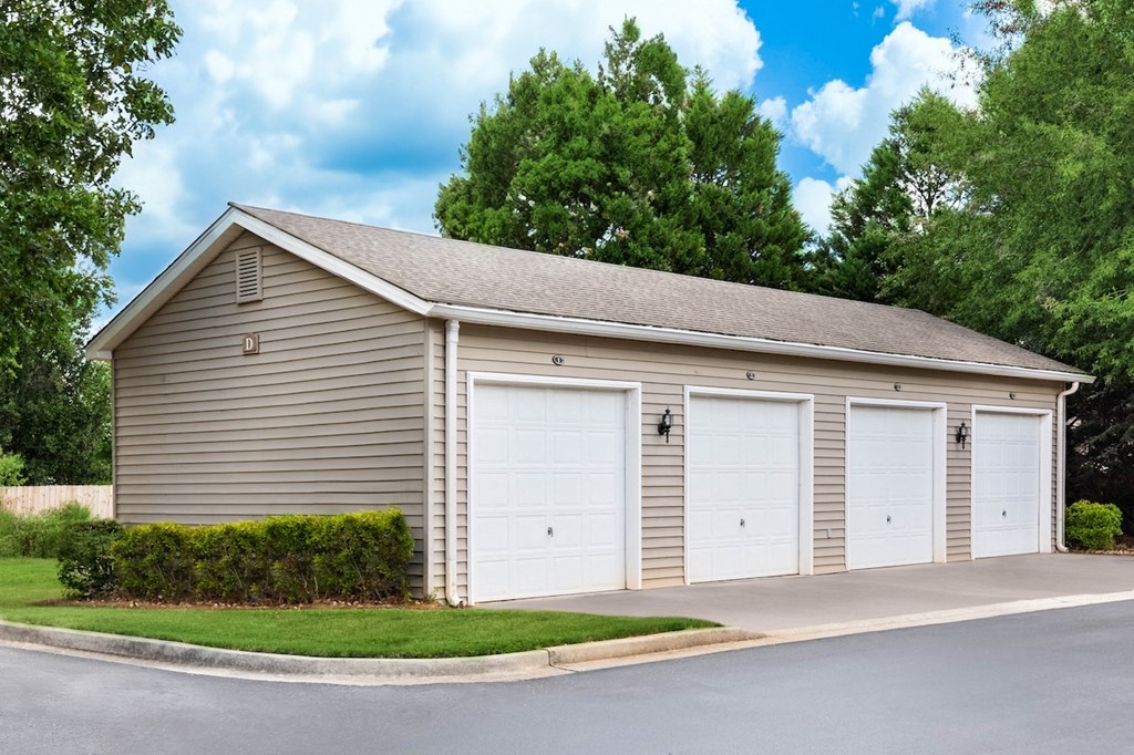 a detached garage with two white garage doors on the side of a street