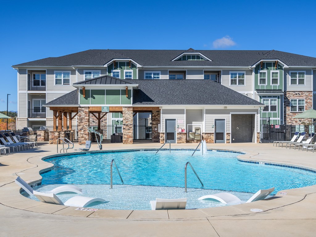 a large swimming pool with chairs in front of a building